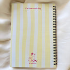 Notebook with yellow and white striped cover on a soft beige background