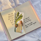 Open book with motivational quote and illustration of a woman holding a plant on a white fabric background