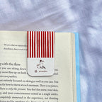 Red and white striped bookmark with fumbledoe logo on an open book