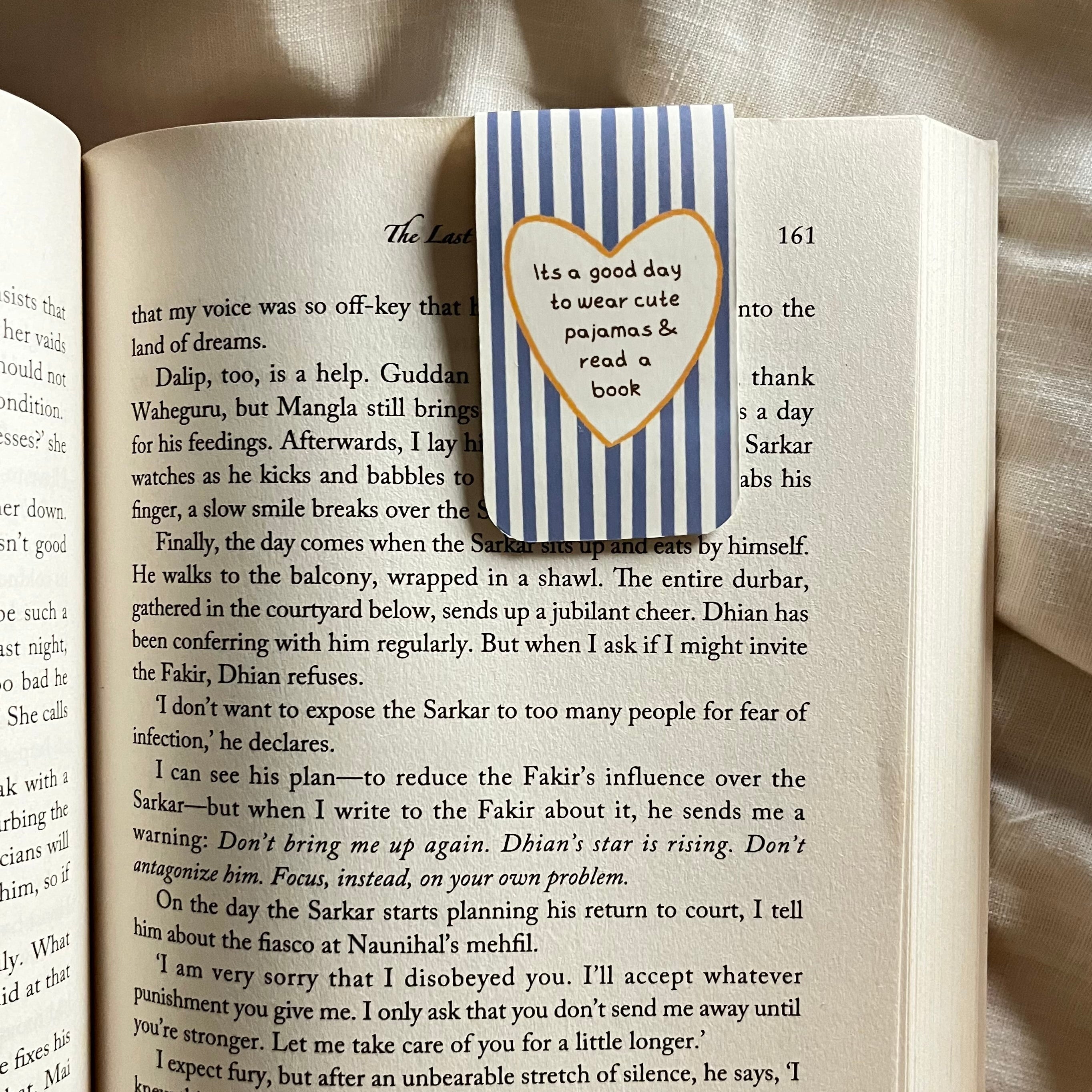 Open book with a heart-shaped bookmark featuring text on a textured surface