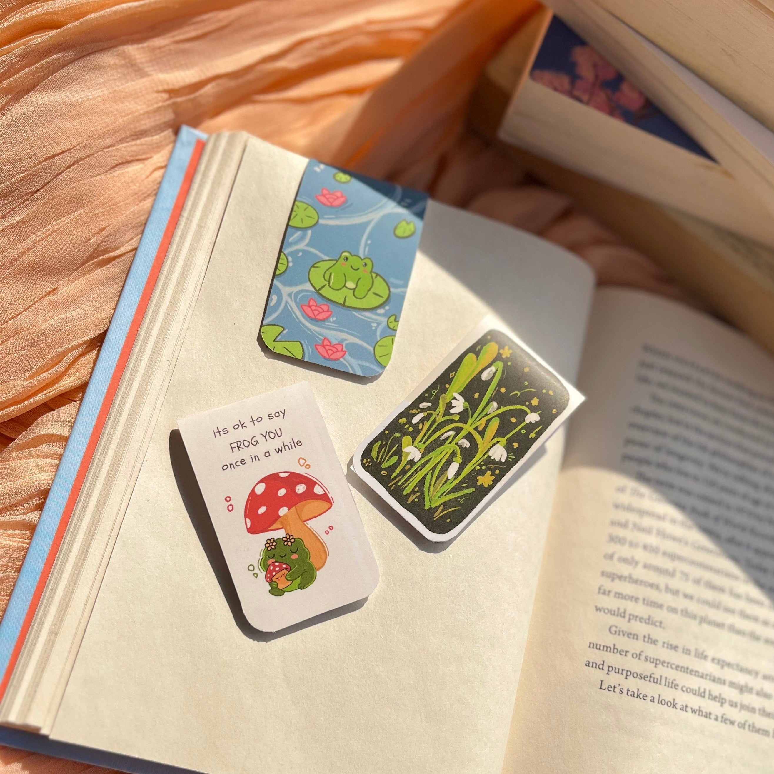 Open book with colorful bookmarks on a soft peach fabric background