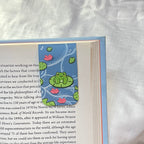 bookmark frog illustration on a white fabric background