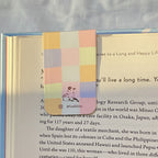 Colorful checkered bookmark with a dog illustration on a book page.