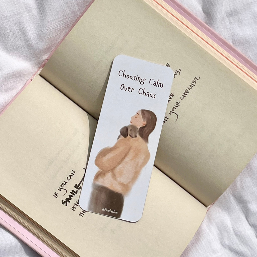 Bookmark with illustration of a woman holding a dog and text 'Choosing Calm Over Chaos' on an open notebook.