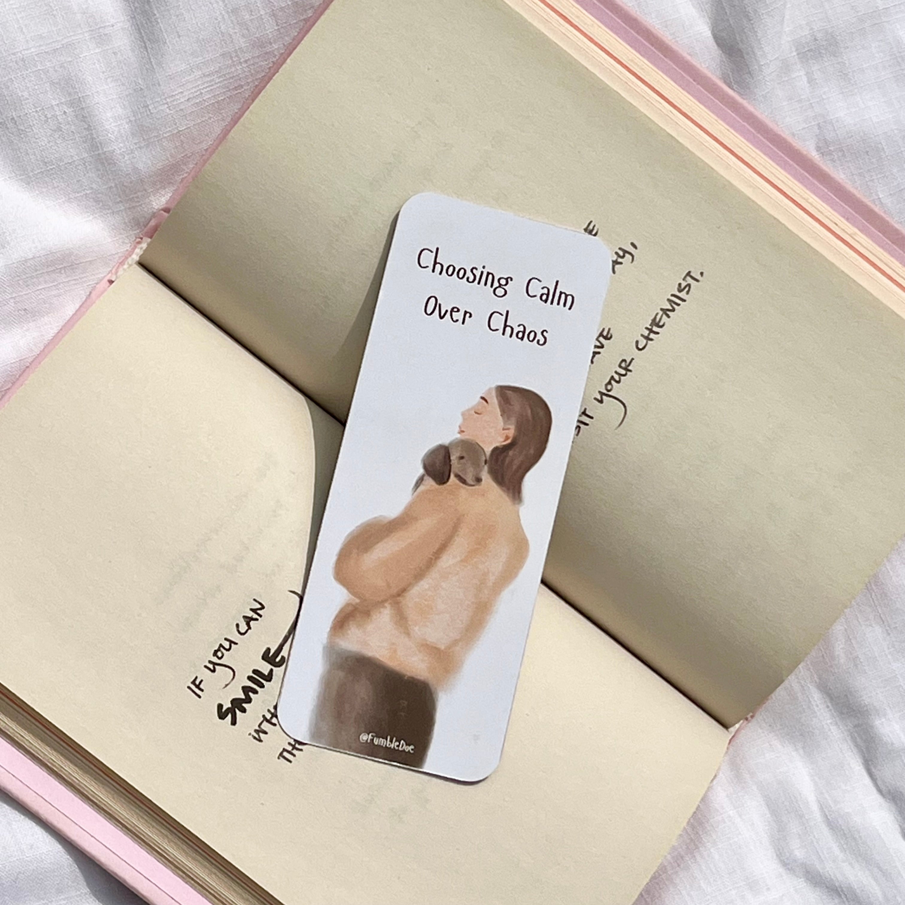 Bookmark with illustration of a woman holding a dog and text 'Choosing Calm Over Chaos' on an open notebook.