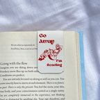 Book with a bookmark titled 'Go Away I'm Reading' on a textured fabric background
