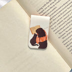 Bookmark with illustration of a person and cat reading a book on an open book