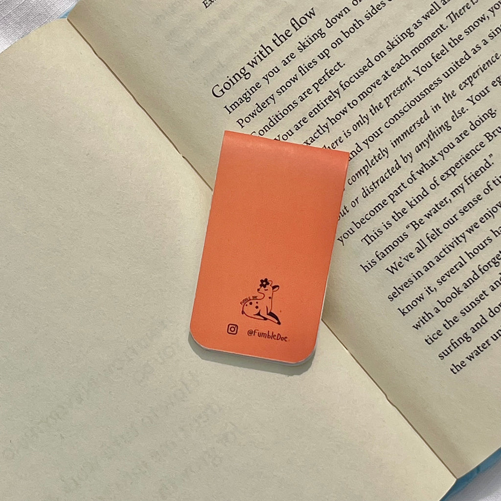 Orange bookmark with a logo on top of an open book