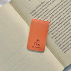 Orange bookmark with a logo on top of an open book