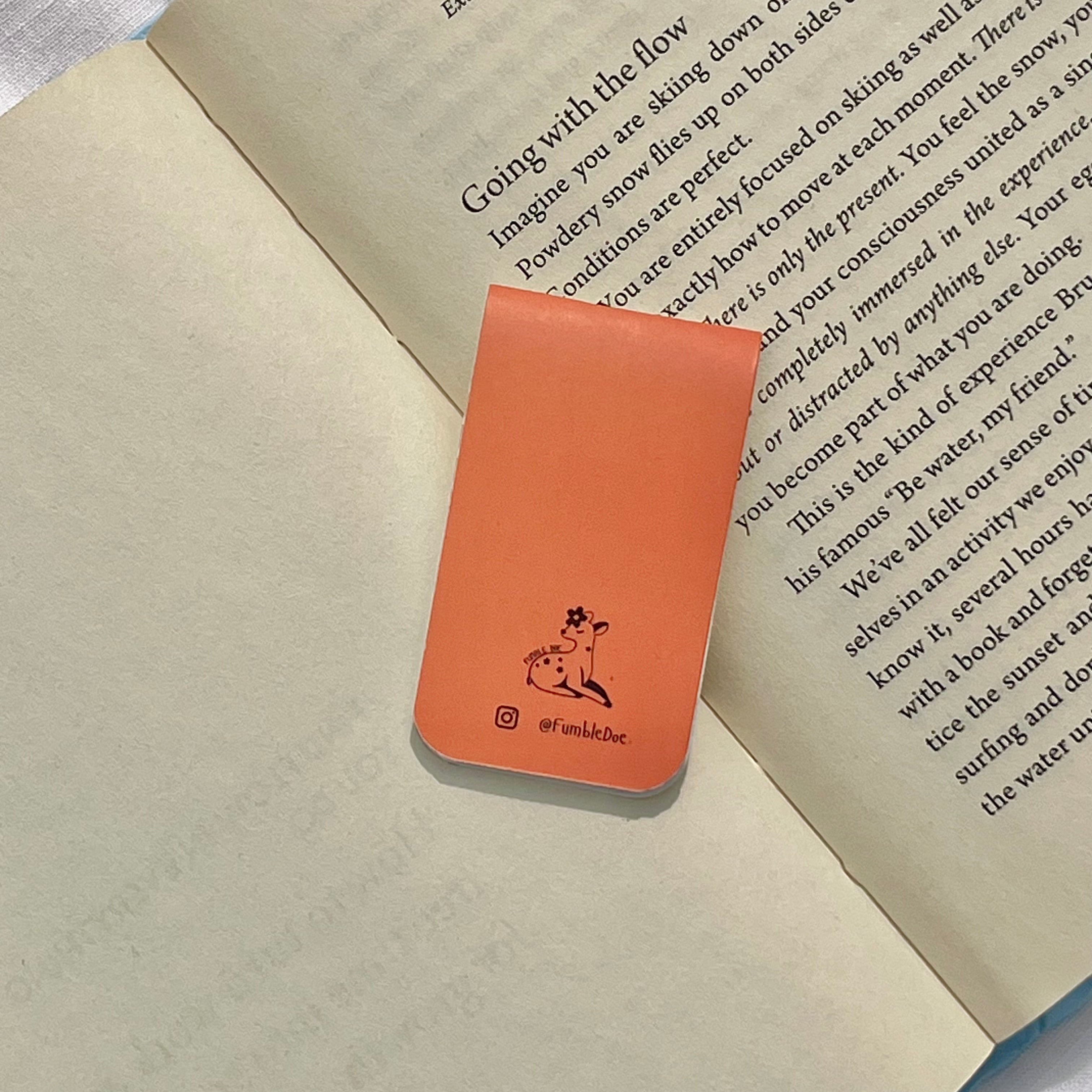 Orange bookmark with a logo on top of an open book