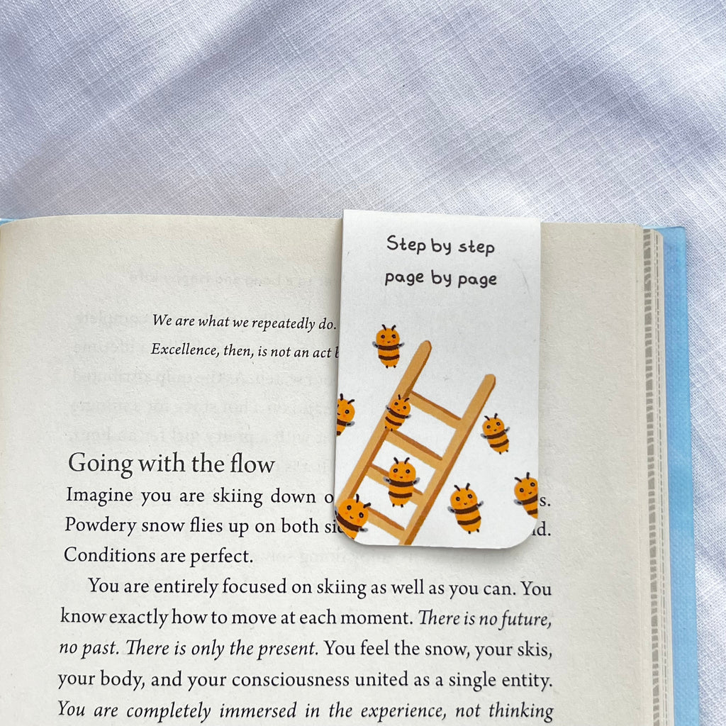 Book with a bookmark featuring a ladder and bees on a blue fabric background