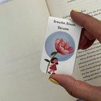 Card with illustration of a girl holding a flower and text 'Breathe. Bloom. Become.' held by a hand.