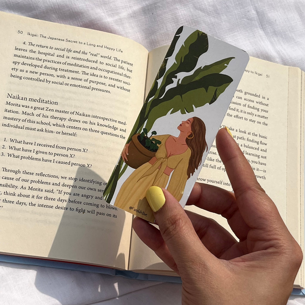 bookmark with a design of a woman holding a plant, over an open book.