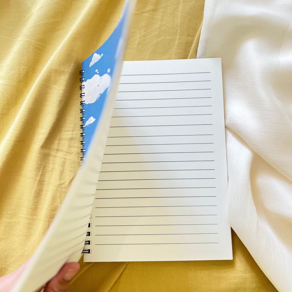 Notebook with lined pages held open against a yellow fabric background