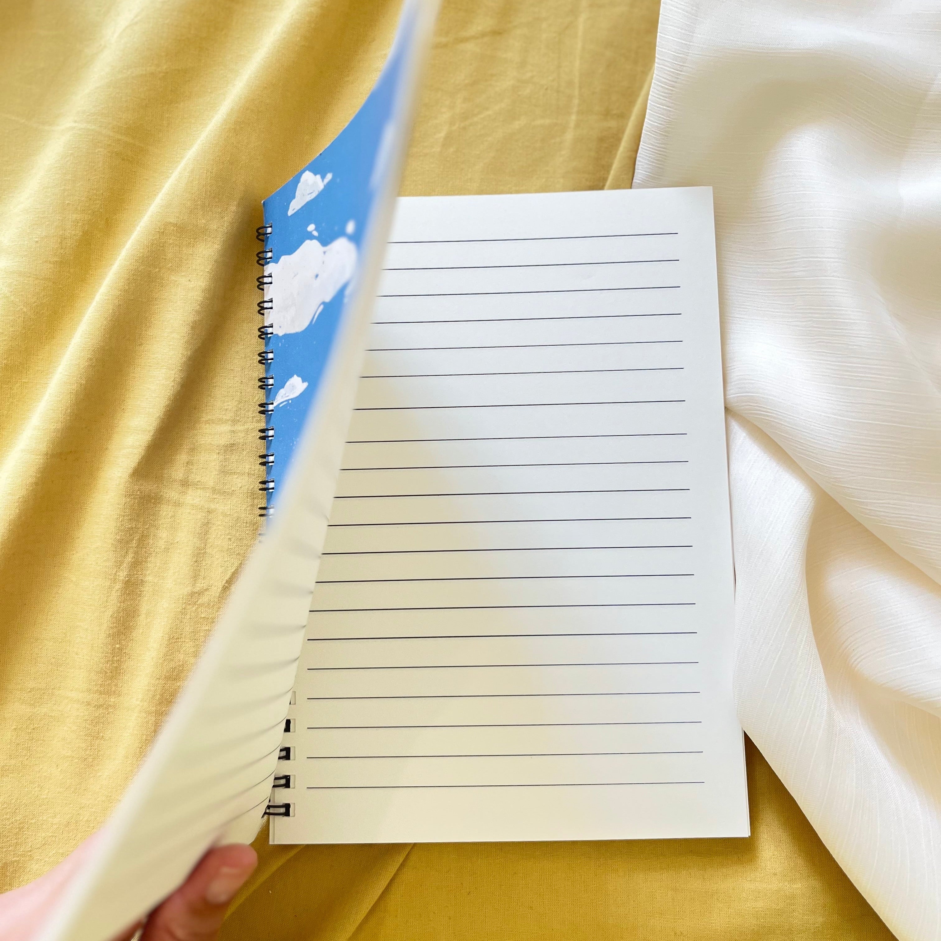 Notebook with lined pages held open against a yellow fabric background
